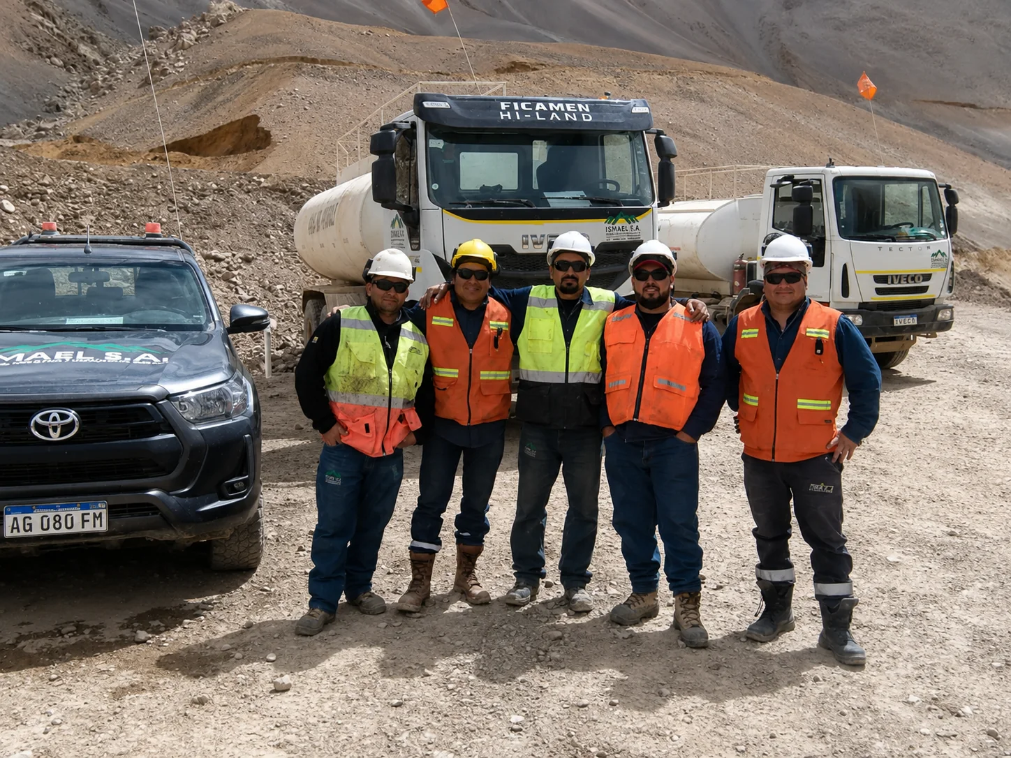 Equipo de ISMAEL S.A. con casco y chaleco reflectante junto a la flota en un frente minero de la cordillera de San Juan